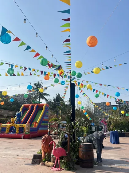 The outdoor venue was transformed into a vibrant jungle with colorful overhead draping, festive buntings, and an expansive play area, ensuring an immersive experience for all the young guests.