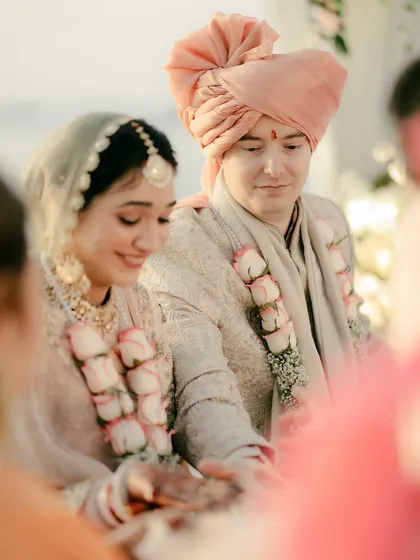 A close-up of the couple performing wedding rituals, their hands joined. The bride's gentle smile and the groom's focused expression capture the solemnity and joy of the moment.
