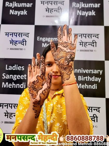 A happy client posing at our studio, showing off her beautiful festive mehndi.