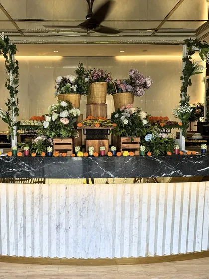 A stunning example of our farmers market theme, featuring a marble-topped counter filled with wicker baskets of fresh flowers and produce. This setup brings a rustic, organic, and vibrant feel to any corporate gathering.
