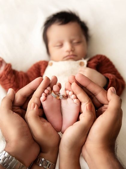 A creative detail shot with the parents' wedding rings on the baby's toes, held within their hands, symbolizing their family's union.