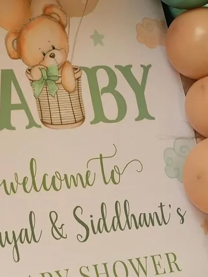 A close-up of the personalized welcome sign for Payal and Siddhant's baby shower. The design incorporates the teddy bear and hot air balloon motif seen throughout the event.