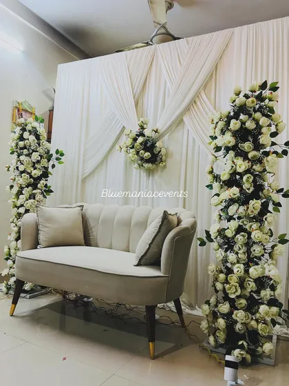 A wider shot of the home Roka setup, showing the two floral pillars framing the seating area. The clean white drapes create a perfect canvas that makes the floral arrangements pop.