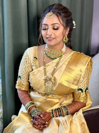A serene moment, with eyes closed to showcase the soft, golden-toned eyeshadow. The makeup is subtle, allowing the richness of the saree and jewelry to take center stage.