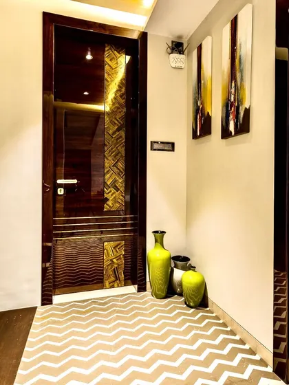The foyer of a luxury triplex we designed. The space is defined by a chevron-patterned floor, a custom door with metallic inlay, and modern art, setting a sophisticated tone for the rest of the home.