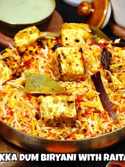 This isn't just any biryani, it's our Paneer Tikka Dum Biryani. Fragrant basmati rice layered with smoky, tandoor-grilled paneer tikka and aromatic spices, served with raita and gravy.