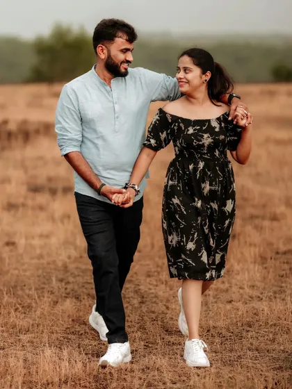 A candid shot of a couple walking and talking in a field, their natural interaction making for a beautiful pre-wedding photo.
