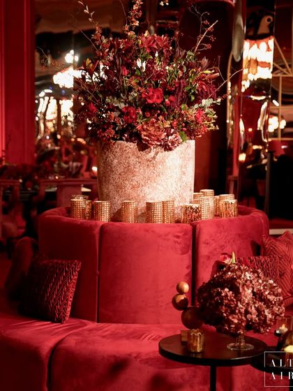 A circular red velvet sofa with a dramatic floral centerpiece at 'Le Rouge'. The design used monotone hues of red to create a classic feel with a lot of oomph and drama.