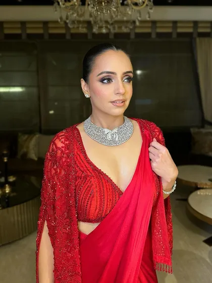 A total bombshell look. This modern take on a red saree features a smokey eye, glowing skin, and a sleek bun for a powerful, chic statement.