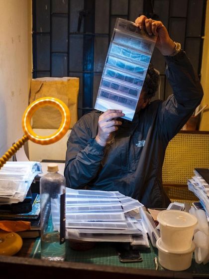 Inspecting newly developed film negatives on a light table. Each frame holds a story, and this is a crucial step in selecting the best images to print in the darkroom.