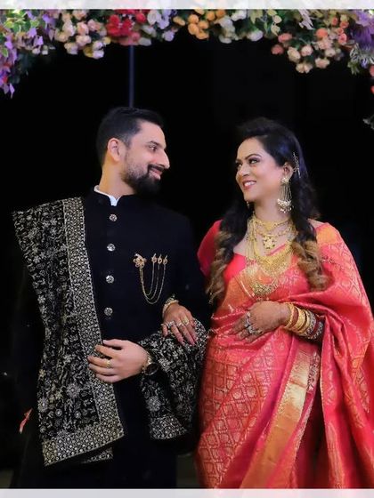 A beautiful portrait of a couple under a floral arch. Their matching smiles and the way they look at each other perfectly capture the happiness of their wedding or reception day.