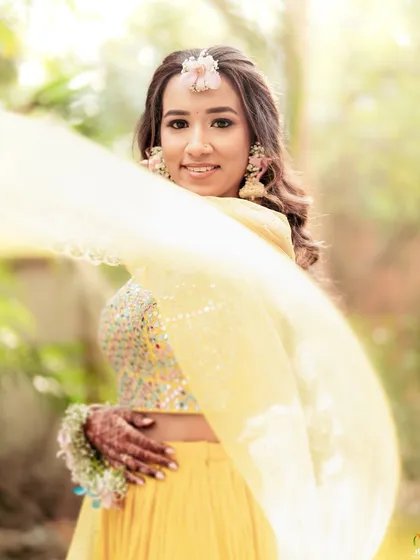 The bride's smile says it all. Her pastel floral jewellery looks beautiful against the bright yellow of her outfit and the flowing dupatta.
