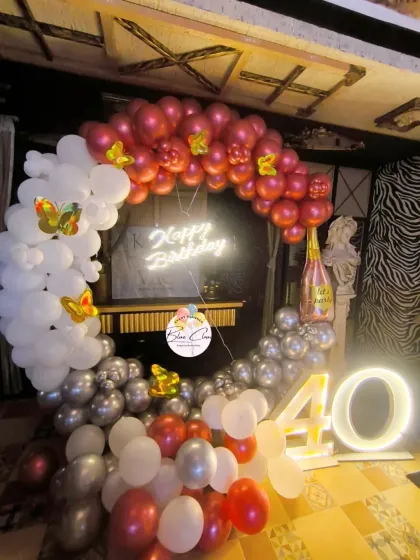 A chic 40th birthday decoration with a balloon ring in red, white, and silver, a neon sign, and a light-up number '40'.