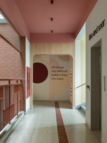 A corridor featuring soft, geometric color blocking and an inspirational quote: "All things are difficult before they are easy." We use design to create a supportive and motivating atmosphere throughout the school.
