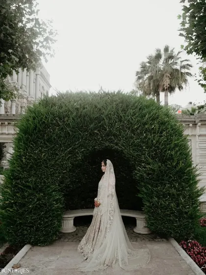 A solitary, elegant portrait of the bride, Roshni, in the gardens of her Istanbul wedding venue. The archway of greenery creates a natural frame, making her look like a character from a classic romance.