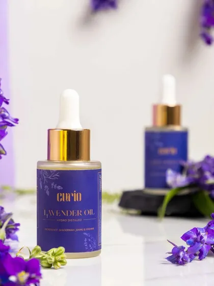 This shot of lavender oil uses a shallow depth of field to draw focus to the main bottle while hinting at a second one in the background. The fresh lavender flowers frame the shot, emphasizing the product's primary natural ingredient.