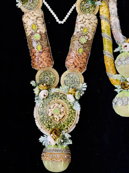 A beautiful dry fruit garland with sections of cashews, almonds, and pistachios, decorated with delicate flowers.