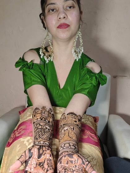 A lovely client showing her full-hand mehendi, which features beautiful Radha-Krishna and peacock designs.