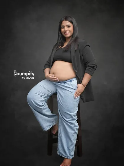 Maternity photos can be modern and chic too. This mom-to-be rocks a casual look with a blazer and jeans, showing off her beautiful bump with confidence and style against a classic studio backdrop.