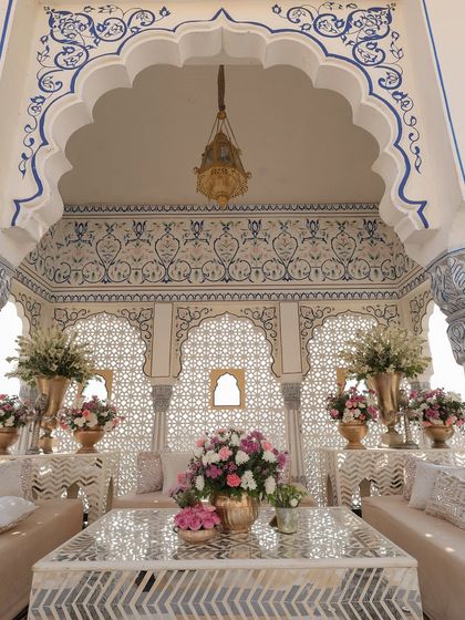 The hand-painted Baradari at the Leela Palace was transformed into a cozy guest lounge. The intricate frescoed alcoves were styled with mirror-work tables and lush floral arrangements, creating an elegant and artistic space.