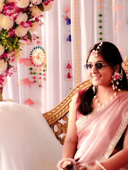 A candid shot of the bride enjoying her Haldi ceremony. The colorful floral decor and her relaxed smile create a warm and festive atmosphere in this photograph.