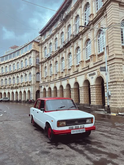 Journeying through time with this classic red and white car. It stands out beautifully against the grand, old buildings of the Fort area.