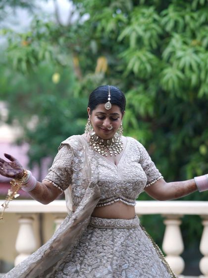 A bride twirls gracefully on a balcony, her lehenga flowing, with lush greenery in the background.