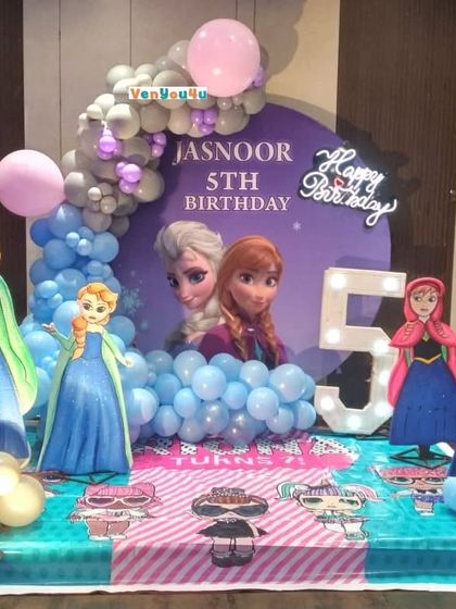 A detailed "Frozen" theme for Jasnoor's 5th birthday, complete with character standees, a custom backdrop, a light-up number '5', and a blue and purple balloon arch.