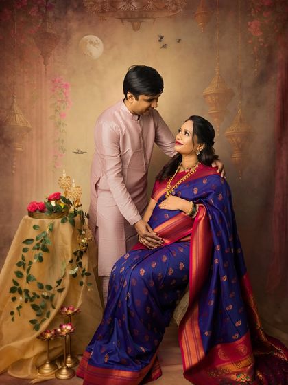 A romantic couple's portrait from a Diwali-themed maternity shoot. The rich blue and red saree shines in the warm, festive light, creating a memory as bright as the festival itself.