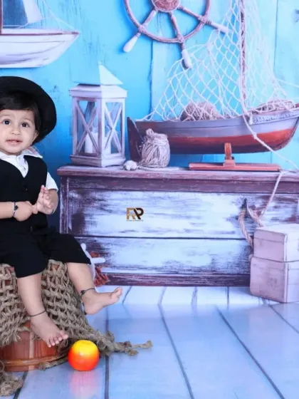 A little sailor sits proudly in a nautical-themed setup, complete with a ship's wheel, lanterns, and a globe. This adventurous theme is perfect for your little explorer.
