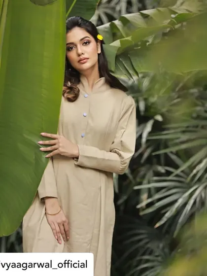 A beautiful shot of Divya Agarwal wearing our beige linen tunic dress amidst lush greenery. The clean lines, mandarin collar, and subtle pleating make this a timeless and elegant piece.