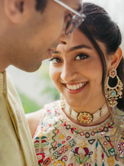 A close-up of a bride's happy, glowing face during her Mehendi. The makeup is fresh and minimal, perfect for capturing these joyful, candid moments.