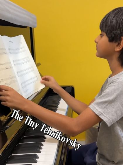 A tiny Tchaikovsky in the making. This young student is focused on his sheet music, demonstrating the discipline and passion that our piano lessons instill from an early age.
