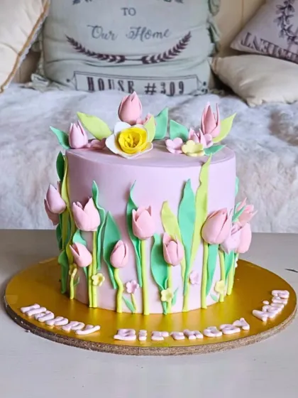 A charming garden-themed cake with a field of hand-sculpted pink tulips growing up the sides.