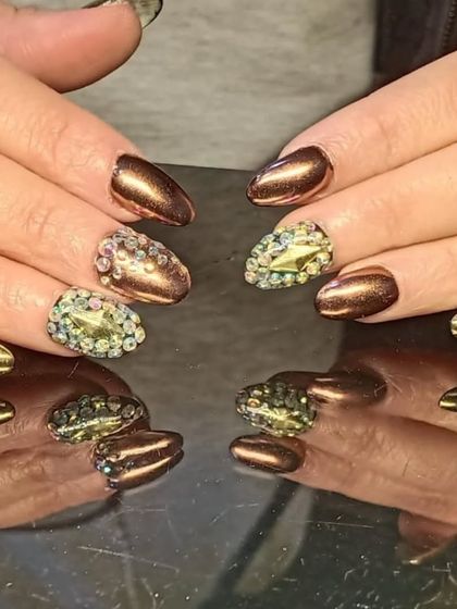 A dramatic manicure with metallic bronze nails and accent nails fully covered in multi-colored rhinestones.