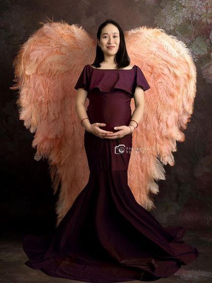 A creative portrait featuring beautiful, large angel wings. This prop adds a touch of fantasy and magic to the maternity session.