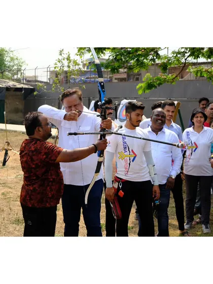 I am guiding Adv. Ashish Shelar as he tries his hand at archery during our anniversary celebration.