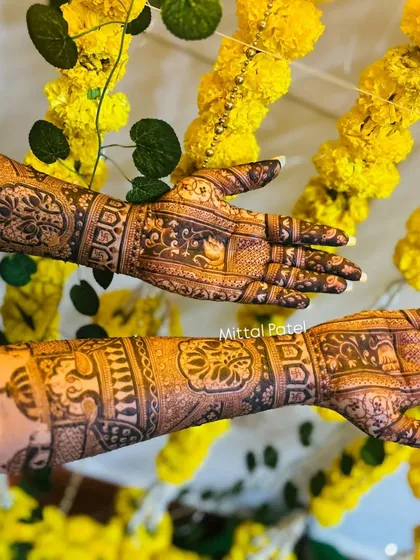 The back of a bridal design, with intricate patterns and elephant motifs, beautifully photographed against a backdrop of marigolds.