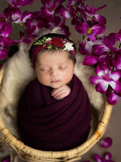 A stunning portrait featuring a deep plum wrap and a matching floral headband, surrounded by vibrant orchids. I love creating rich, colorful palettes.