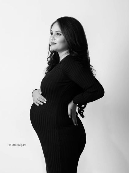 A thoughtful and elegant solo maternity portrait in black and white. The simple, fitted dress and classic profile pose beautifully highlight the graceful curve of her baby bump.