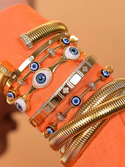 Creating a stack has never been easier. I love mixing textures and styles, like these chunky snake bangles with delicate evil eye pieces.