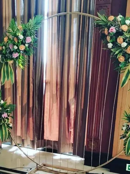 This photo shows a simple yet elegant circular metal frame decorated with four arrangements of fresh flowers and leaves. This kind of versatile backdrop can be used for any type of party and serves as a beautiful frame for photos.
