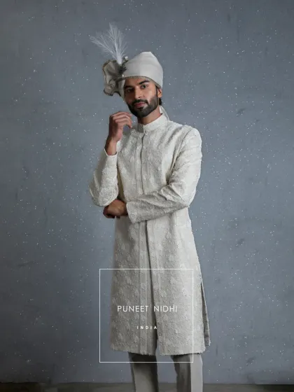This ivory sherwani is a creation of soul and craft, embellished with 3-dimensional florals that rise gently from the fabric. It celebrates the spirit of weddings as a journey of heritage.