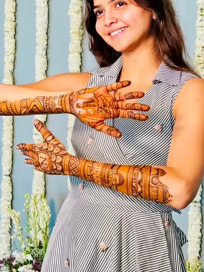 A happy client showing off her engagement mehndi, which is detailed but lighter than a full bridal design.