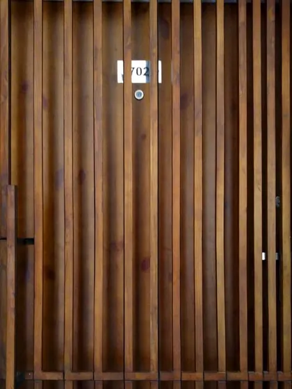 A detail shot of the main door for the Gurgaon residence, where vertical wooden slats of varying spacing create a dynamic, textured facade that plays with perspective.