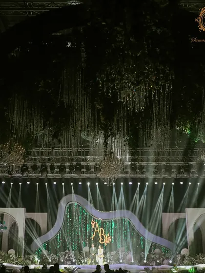 The stage was designed to be both grand and elegant, featuring a massive, glittering backdrop with the couple's monogram. The lighting and overhead installations created a truly cinematic focal point for the evening.