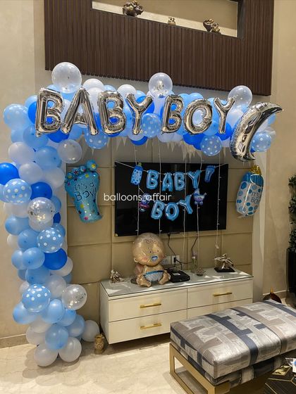 A 'Baby Boy' balloon arch setup designed to frame a TV unit, making it a central feature of the home party decoration.