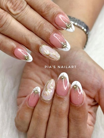 A lovely combination of a classic white French tip, gold starburst charms, and a delicate encapsulated gold flower.