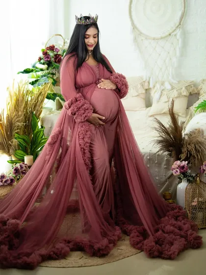This elegant maternity robe with ruffled sleeves and hem adds a layer of softness and luxury. The mom-to-be cradles her bump in our beautifully styled boho studio setting.