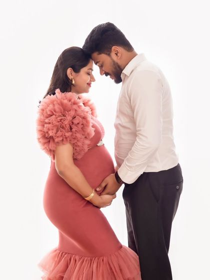 An intimate forehead-to-forehead pose, capturing the deep connection between the expecting couple in a minimalist setting.